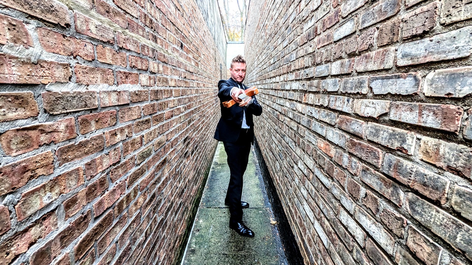 JD Kostyk holding a guitar in formal attire